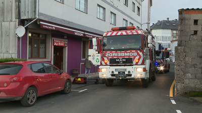 Bombeiros ao pé do edificio incendiado, en Sigüeiro