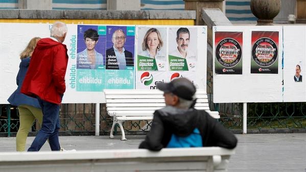 Cidadáns observan carteis electorais en San Sebastián (EFE/Juan Herrero)