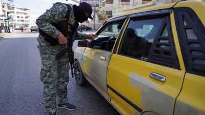 Un membro das forzas de seguridade sirias supervisa a identidade